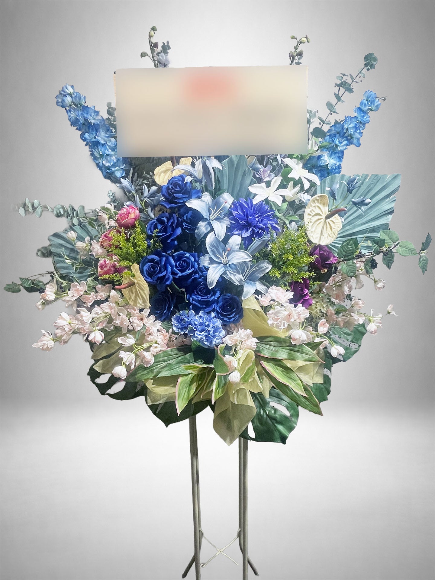 ブルーローズとユリを中心にアレンジされた、Re:Bloomシリーズのアーティフィシャルスタンド花。ライトグリーンのアンスリウムやピンクの花材がアクセントになった、涼やかで品格のあるデザイン