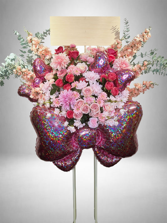 ピンクのダリアやローズにグリッターリボンとハートバルーンをあしらったRe:Bloomシリーズのスタイル装花