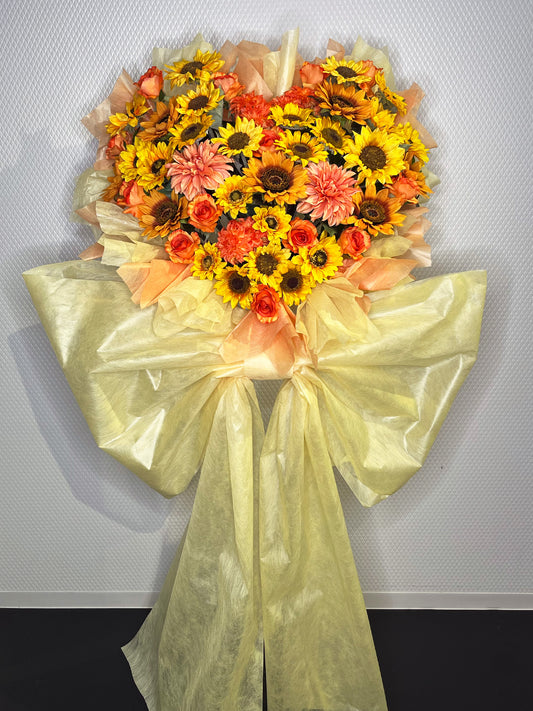 ひまわりとオレンジローズを中心にハート型にまとめたRe:Bloomシリーズのビタミンカラー装花