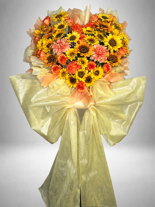 ひまわりとオレンジローズを中心にハート型にまとめたRe:Bloomシリーズのビタミンカラー装花