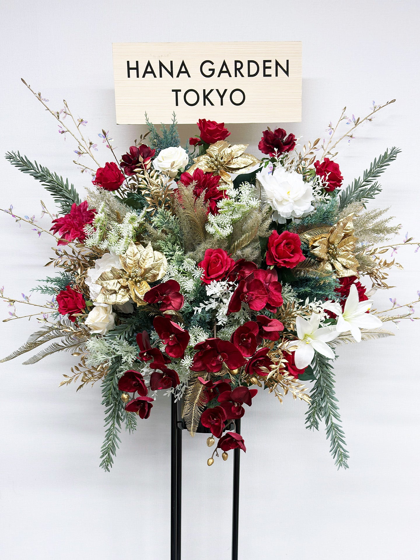 深紅とホワイト、ゴールドが調和したクラシカルで上品なスタンド花。
アーティフィシャルフラワーを使用した華やかな祝花で、公演祝い・周年祝いに最適。
