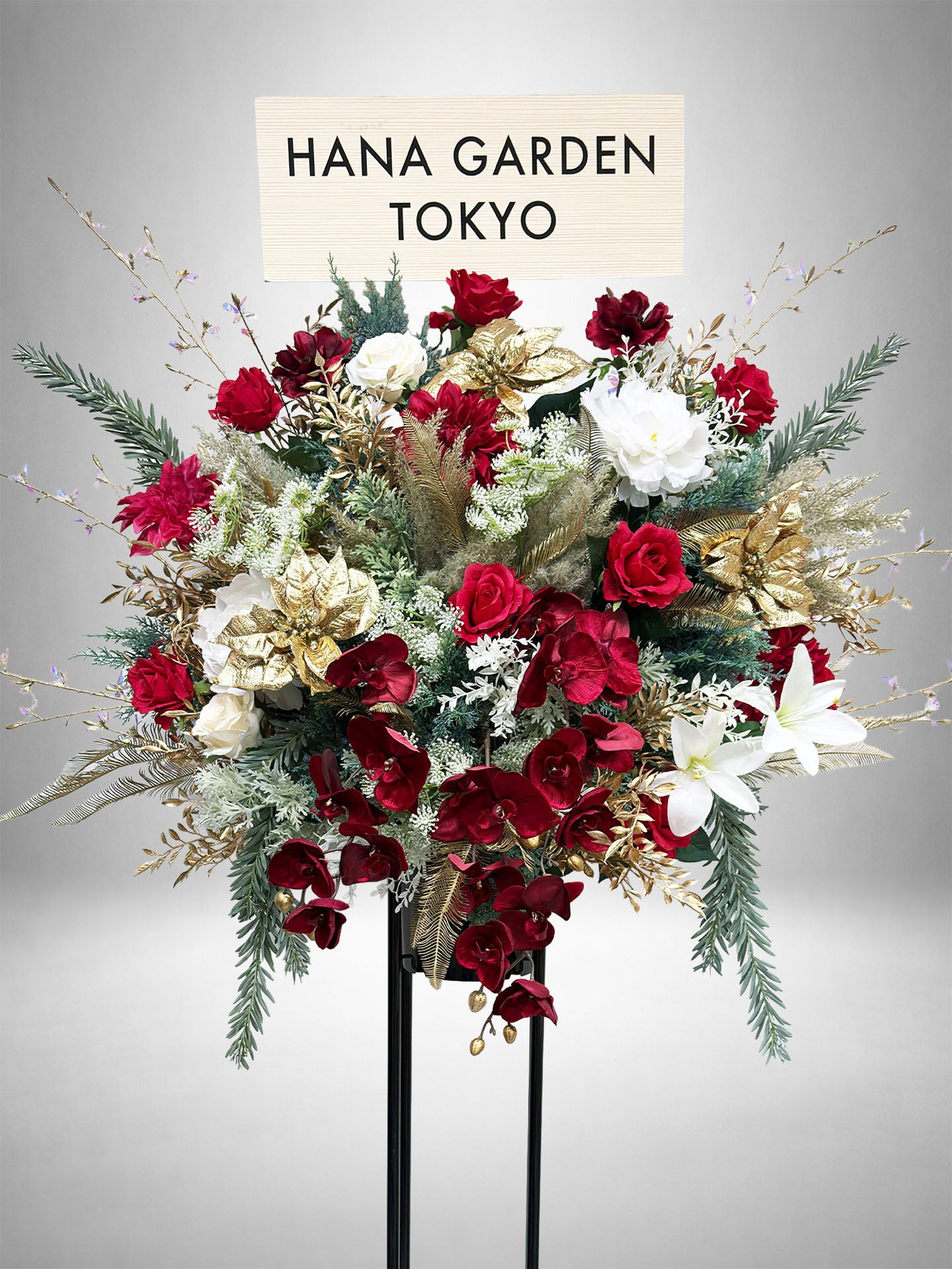 深紅とホワイト、ゴールドが調和したクラシカルで上品なスタンド花。
アーティフィシャルフラワーを使用した華やかな祝花で、公演祝い・周年祝いに最適。