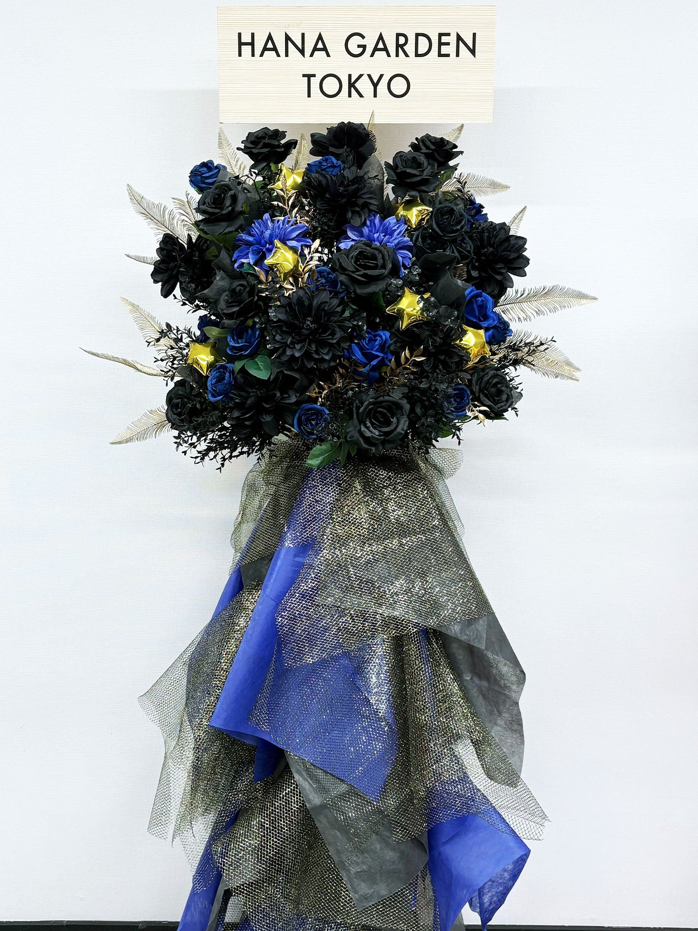 HANA GARDEN TOKYOのRe:Bloom ノワールブルースタンド花。ブラックとブルーの花々にゴールドアクセントを加えたクールで重厚感のあるアーティフィシャルフラワーのスタンド花。
