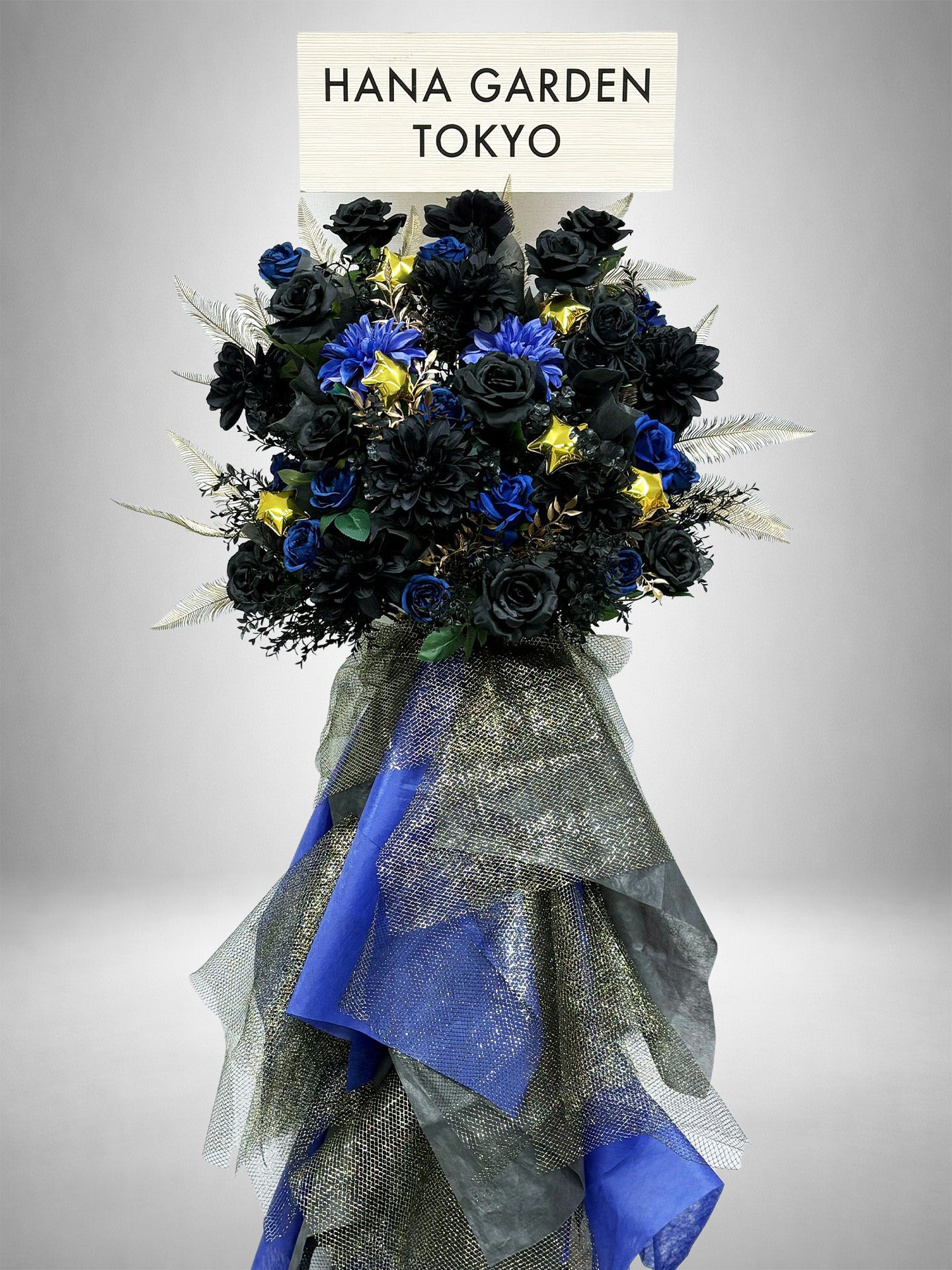 HANA GARDEN TOKYOのRe:Bloom ノワールブルースタンド花。ブラックとブルーの花々にゴールドアクセントを加えたクールで重厚感のあるアーティフィシャルフラワーのスタンド花。
