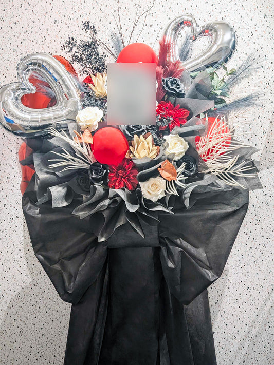 ブラックの花材とゴールドバルーンを組み合わせたシックで華やかなスタンド花。エレガントな雰囲気が舞台やライブの空間を印象的に彩るデザイン