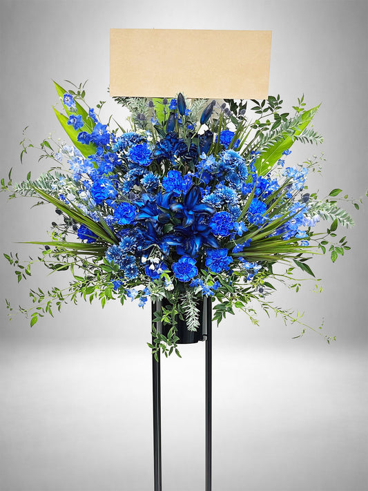 深いブルーとグリーンのコントラストが印象的なスタンド花。
リリーやカーネーションを使用した上品でスタイリッシュな生花デザイン。
