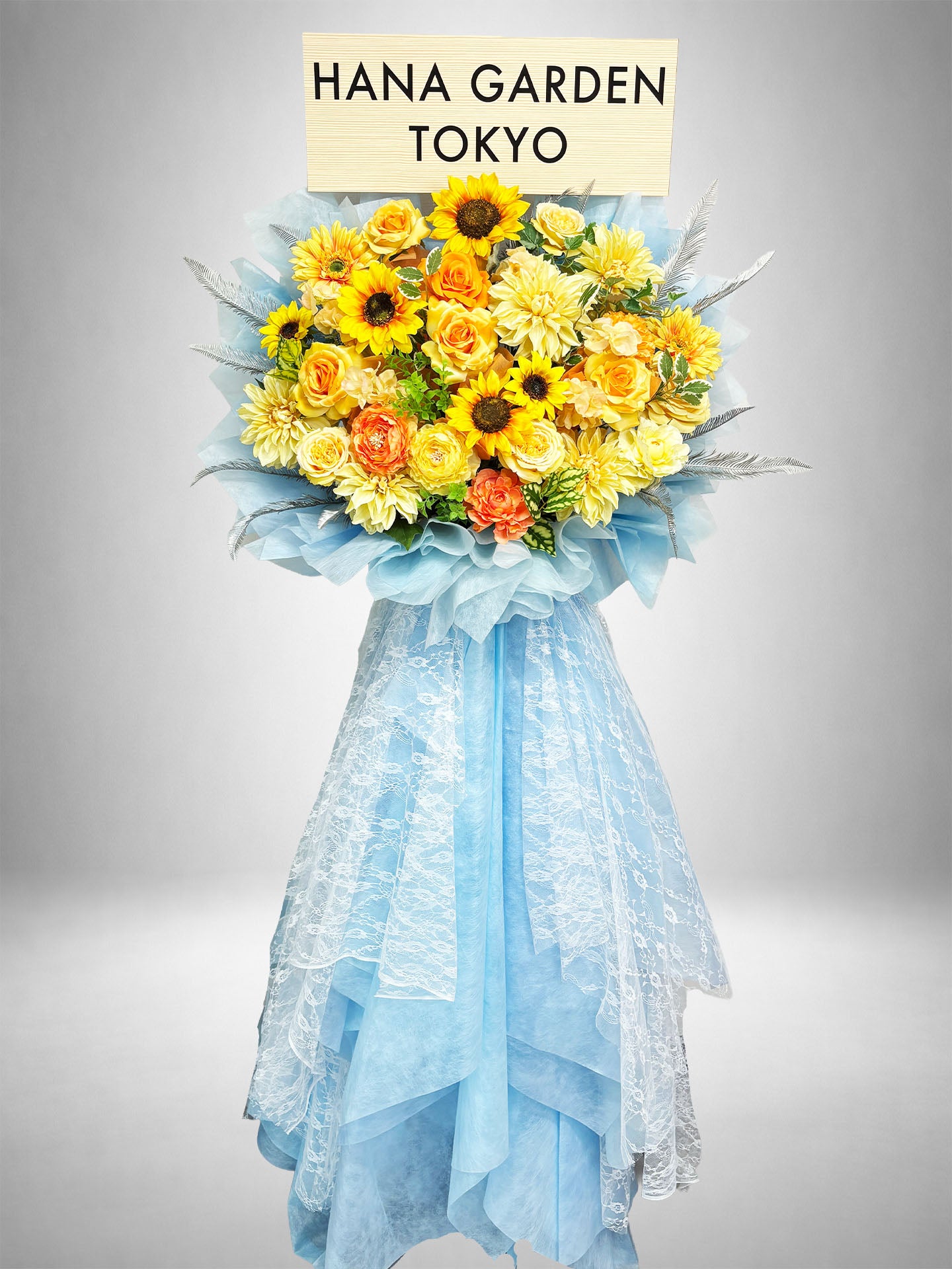 [Re:Bloom] サンフラワーブリーズスタンド｜ひまわり・イエロー・オレンジの花々と爽やかなブルーのラッピングを組み合わせた華やかなスタンド花