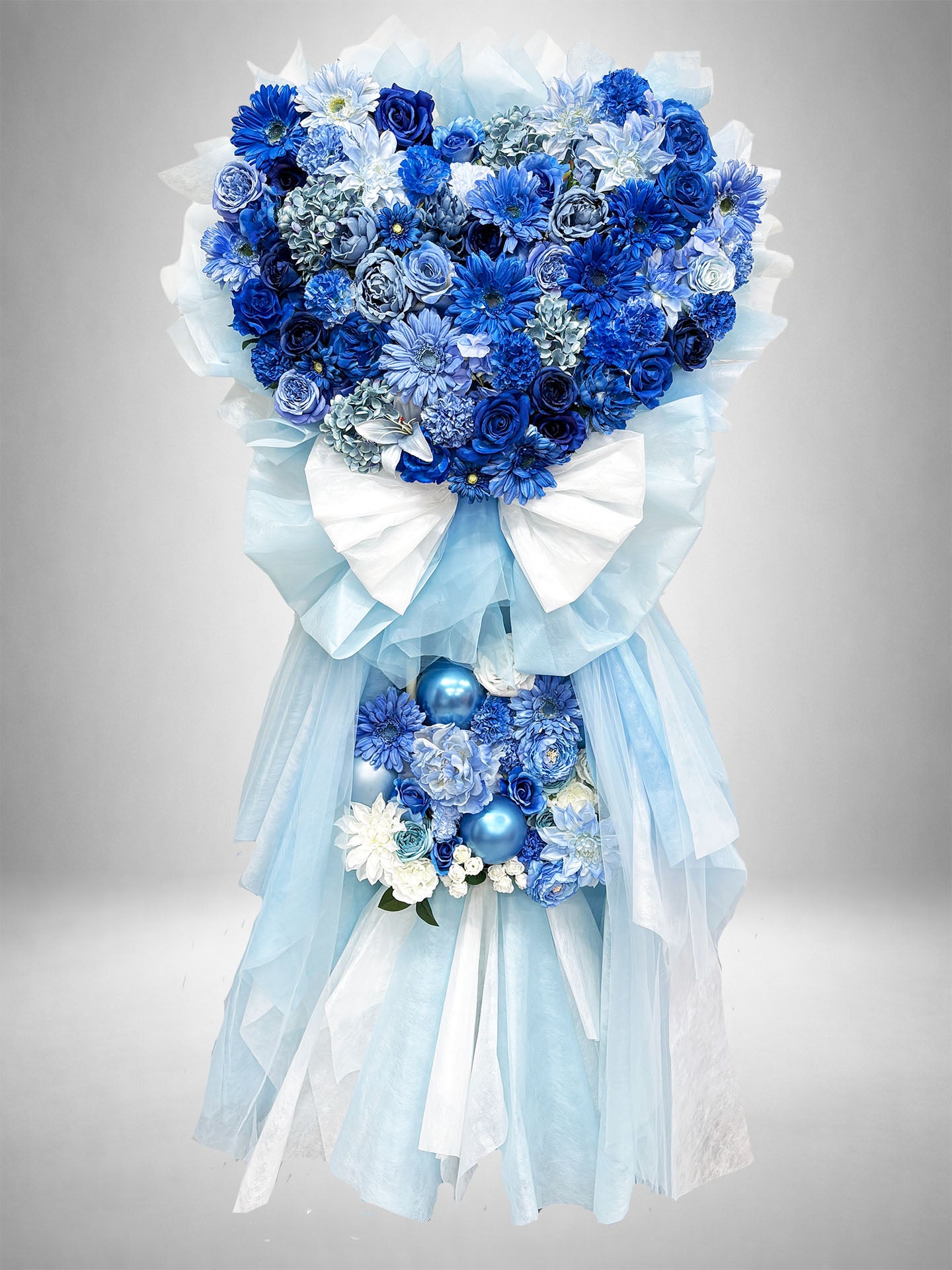 [Re:Bloom] ブルーハートグレイススタンド｜ブルー・ライトブルー・ホワイトの花々をハート型にアレンジし、ブルーパールをあしらった華やかなスタンド花