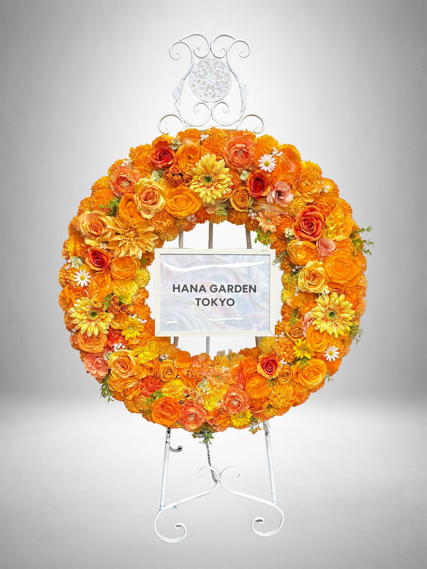 オレンジとイエローの花々を円形にアレンジしたシトラスオレンジリーススタンド