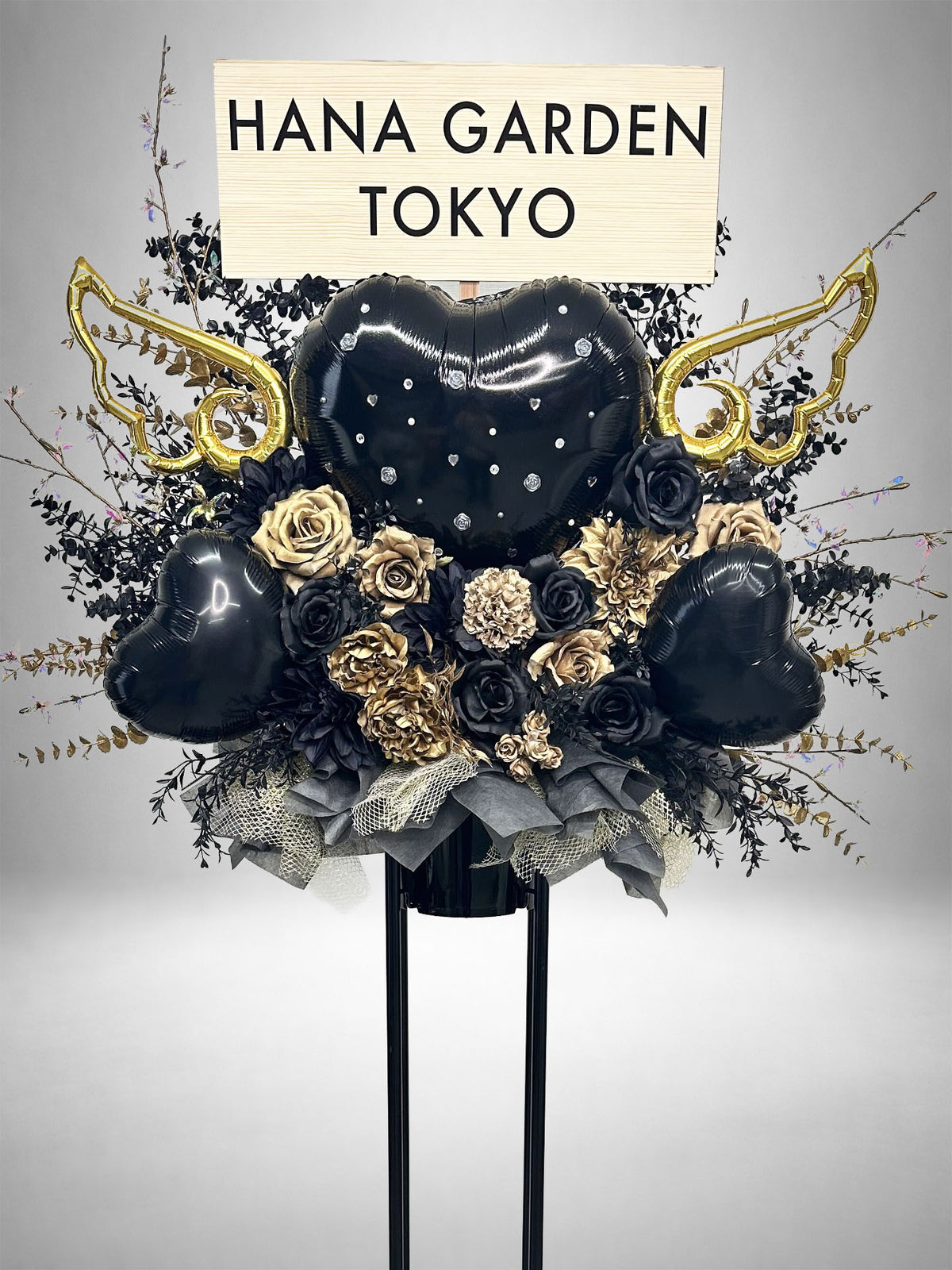 ブラックとゴールドの花々に黒いハートバルーンとゴールドの羽根を組み合わせたブラックゴールドエンジェルスタンド