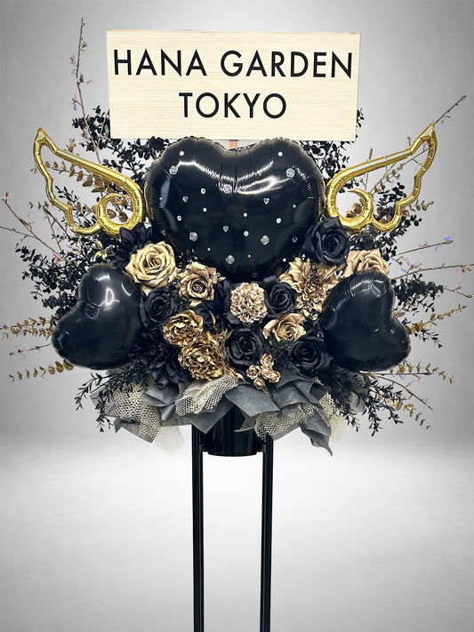 ブラックとゴールドの花々に黒いハートバルーンとゴールドの羽根を組み合わせたブラックゴールドエンジェルスタンド