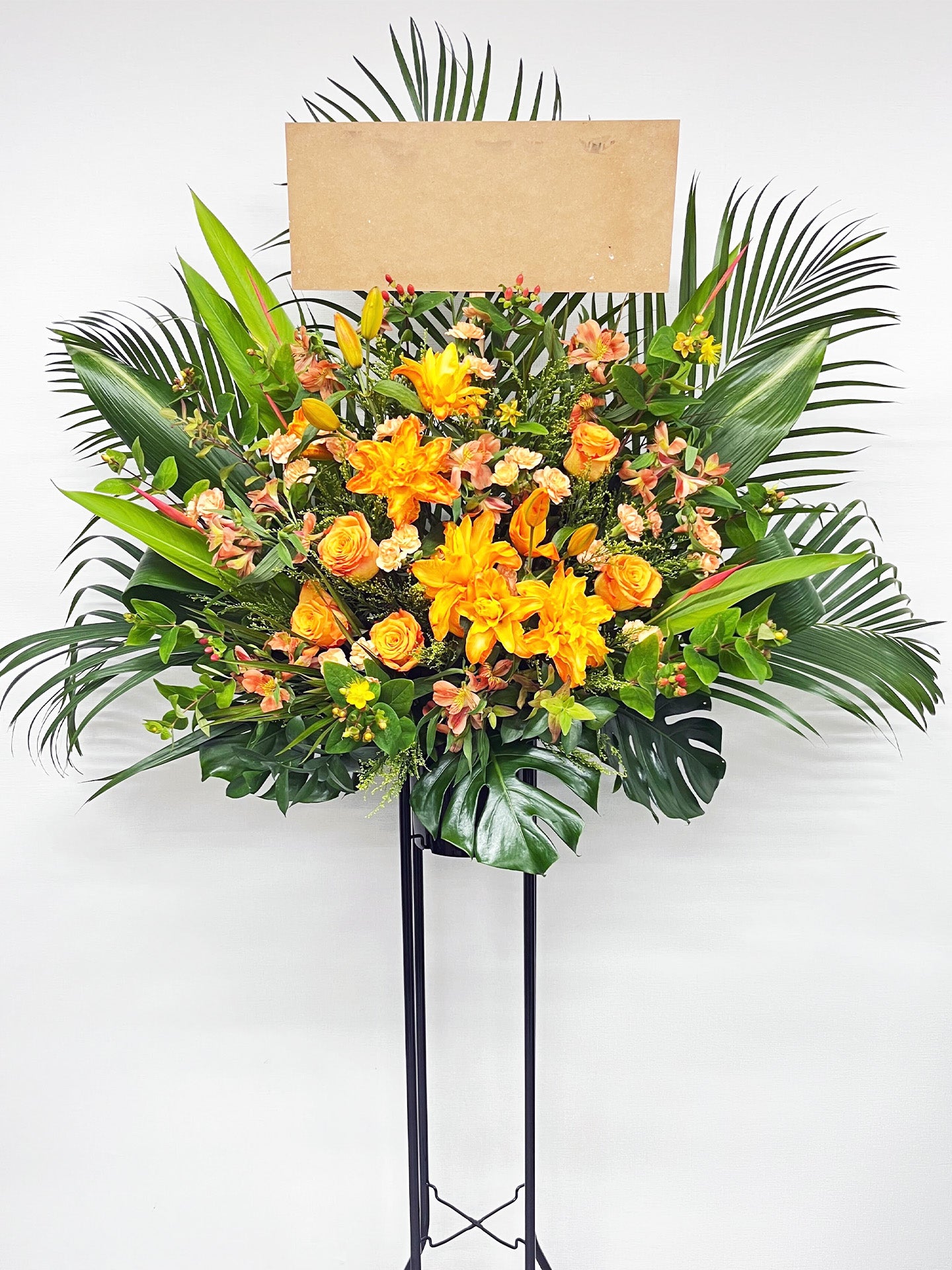 明るいオレンジの花々が太陽のように輝く、華やかでラグジュアリーなスタンド花。
リリーやローズを使用した生花デザインで、公演祝いや開店祝いに最適。