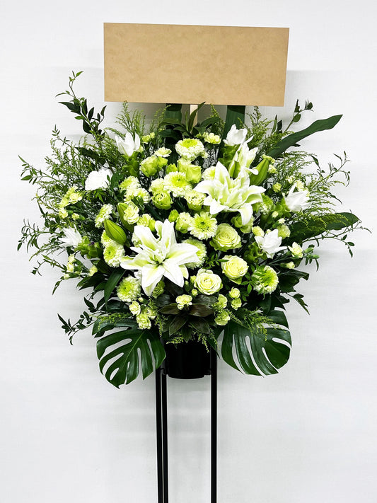 白と淡いグリーンの花々が織りなす清楚で上品なスタンド花。
ユリやローズを中心にした柔らかく明るい生花デザイン。
